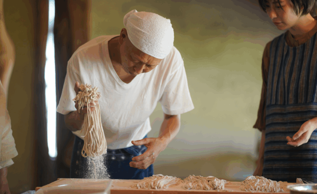外国人客の前で蕎麦を打つそば屋の店主
